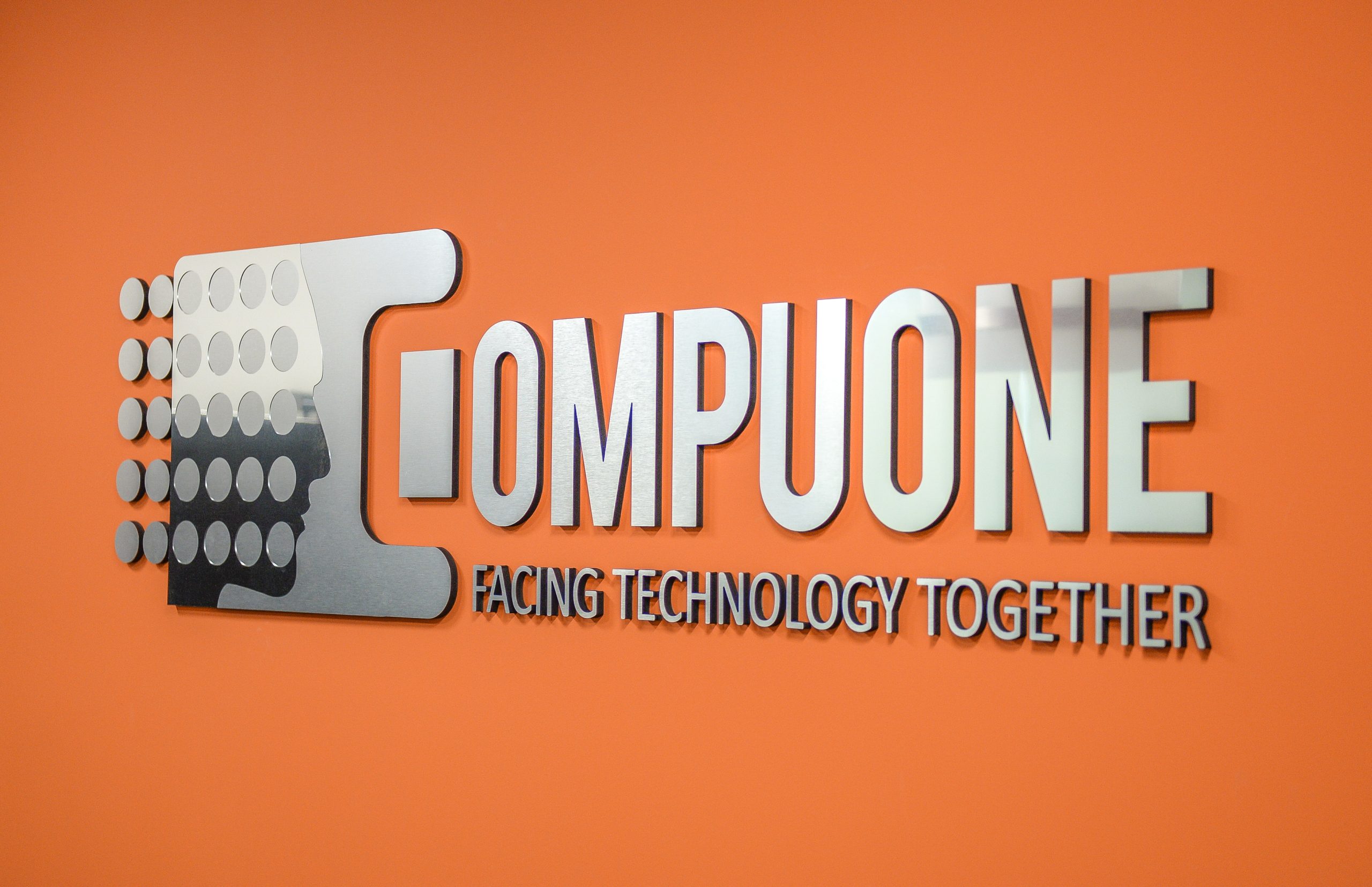 CompuOne sign in the office on an orange wall.
