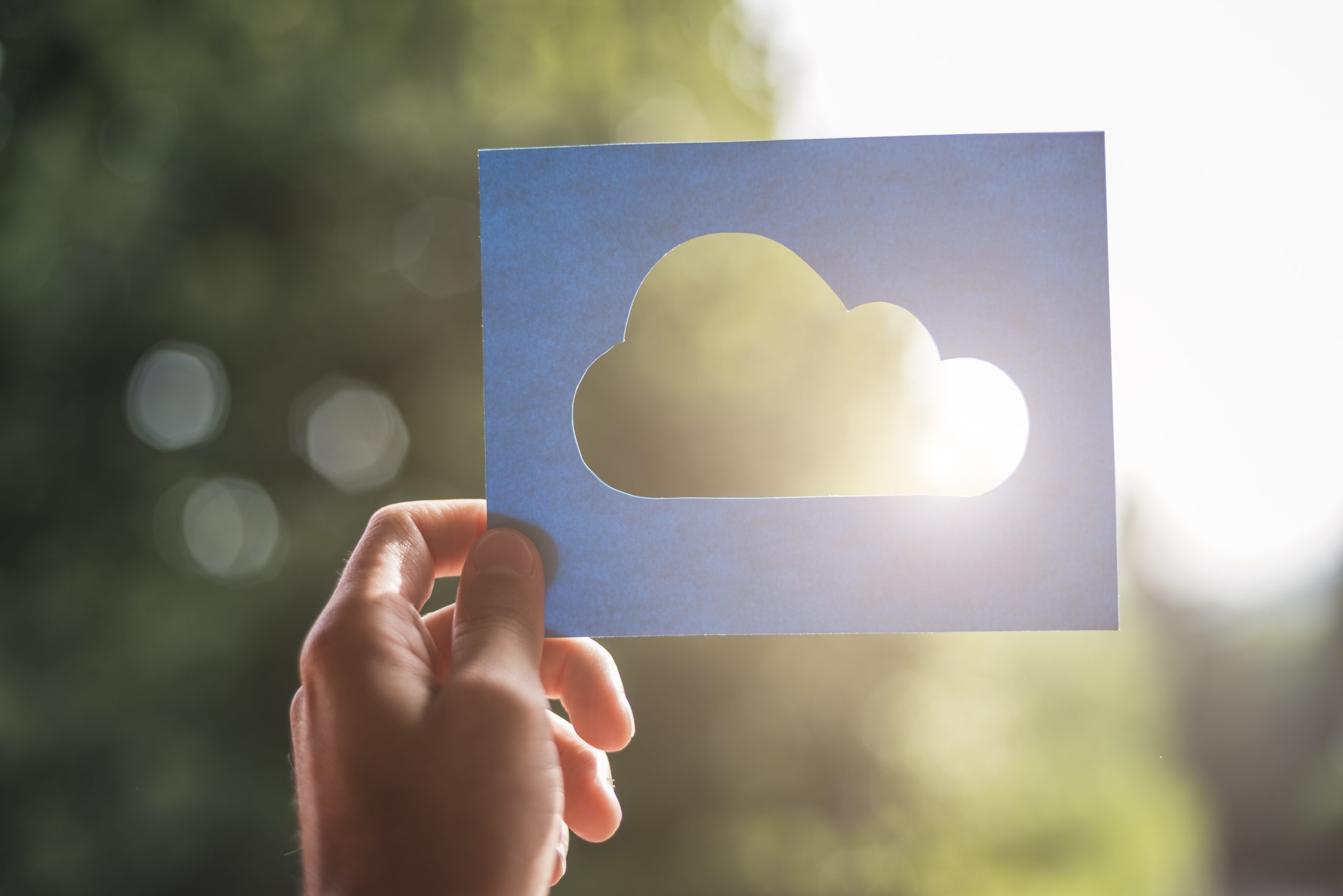 Person holding up a cloud computing symbol to the sun.