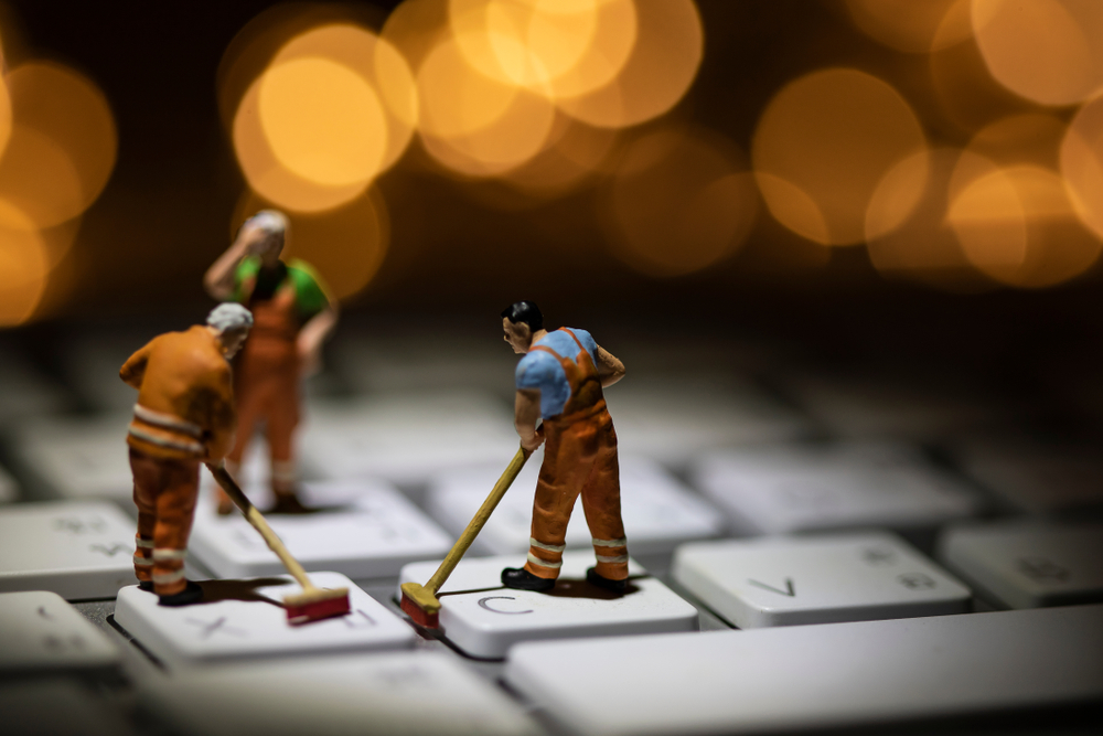 Janitor miniature figures cleaning the keyboard of a computer.
