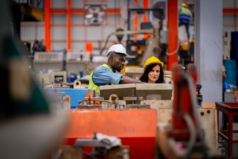 Male and female engineers working on metal sheets.