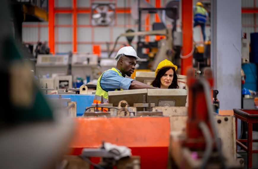 Male and female engineers working on metal sheets.
